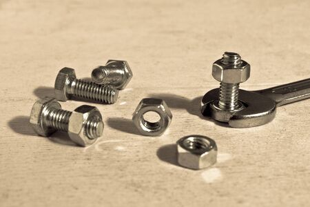 Metallic bolts and nuts with open-end wrench. Still-life picture taken in studio on wooden table.の写真素材