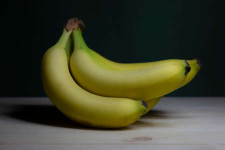 Banana on a wooden table. Low-key still-life photo, made on studio with black background and softboxの写真素材