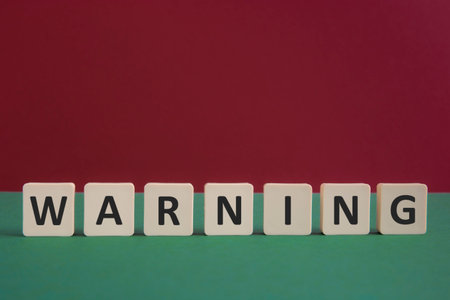 Word WARNING written with leisure game tiles. Conceptual image representing a textual message communicated using letters from a board game.の写真素材