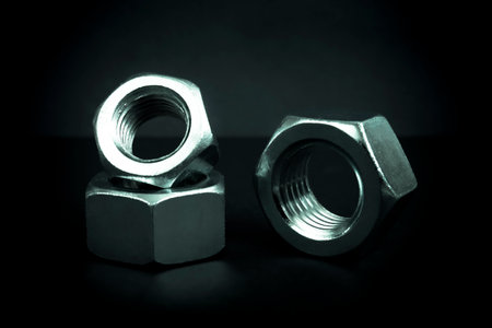 Metallic nuts. Low-key concept picture taken in studio with soft-box and dark background representing some mechanical components.の写真素材