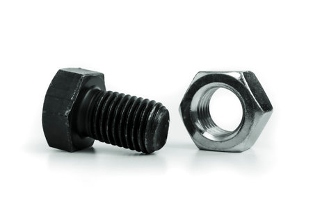 Metallic nut and black bolt. Picture taken in studio with soft-box and dark background representing some mechanical components.の写真素材