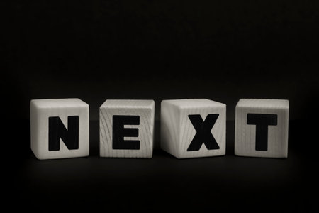 Word NEXT written with wooden cubes. Studio shot of some arranged wooden blocks with a textual message.の写真素材