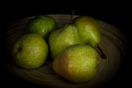 Pears in a friut bowl. Still life low-key picture taken in studio using light painting technique.の写真素材