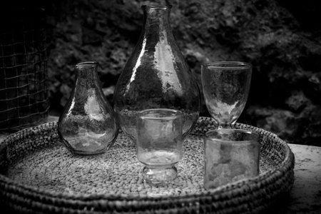 Old glass containers. Collection of retro bottle, amphorae and glasses placed on a wicker tray.の写真素材