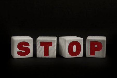 Word STOP written with wooden cubes. Studio shot of some arranged wooden blocks with a textual message.の写真素材