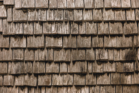 Old wooden tile roof. Pattern of a roof made of small wooden panels aged and marked by time and wear.の写真素材