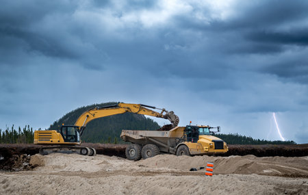 Excavator and dumper at work on a construction site with stormy sky