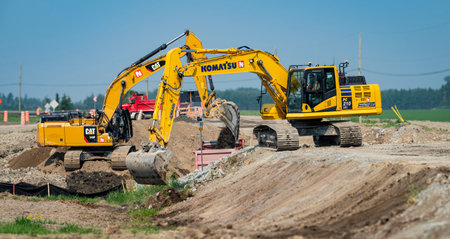 Rouyn-Noranda, Quebec, Canada, June 6, 2023, Two excavators working on repairing a rural road, with a blue skyのeditorial素材