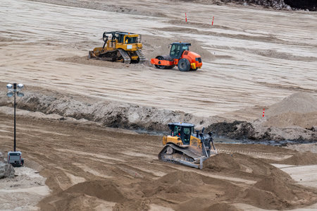 Yellow and black bulldozer pushing sand onto a construction site