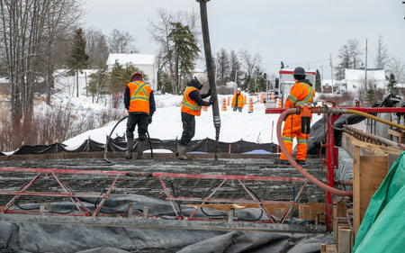 Workers pouring concrete using a concrete pump to build a slab, winter