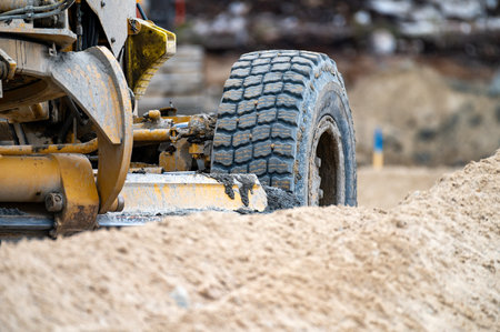 Isolated view of a wheel of a grader working in sand