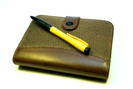 yellow-black ball-point pen on a notebook with leather flightの写真素材