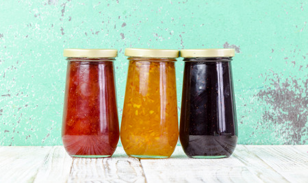 Homemade jars of fruits jam on rustic wooden backgroundの写真素材