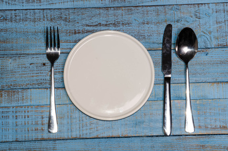 Blank plate with fork and knife on tablecloth backgroundの写真素材