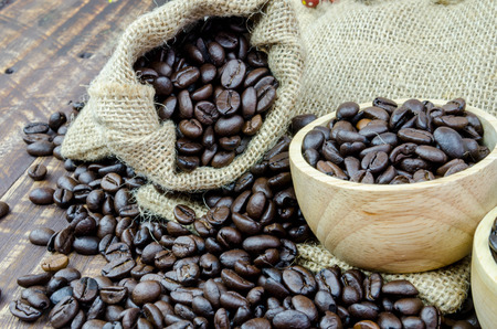coffee beans and wooden bowl full of ground coffee on the table backgroundの写真素材