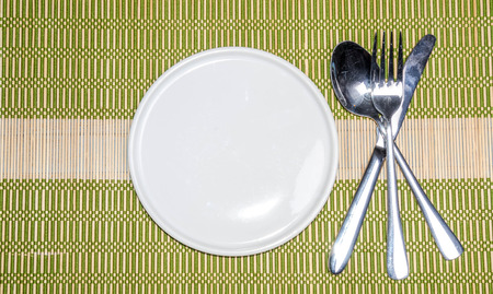 Blank plate with fork and knife on tablecloth backgroundの写真素材
