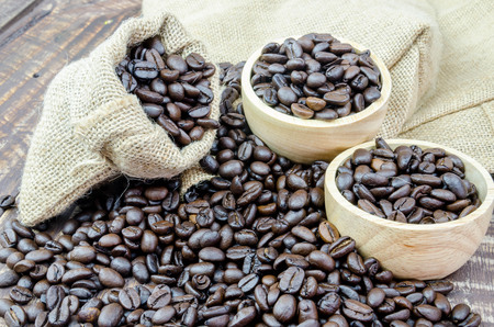 coffee beans and wooden bowl full of ground coffee on the table backgroundの写真素材