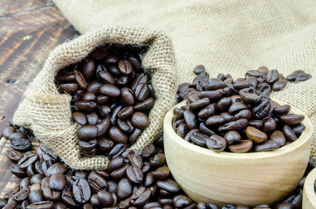 coffee beans and wooden bowl full of ground coffee on the table backgroundの写真素材