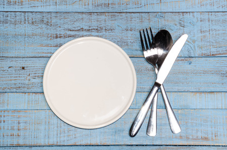 Blank plate with fork and knife on tablecloth backgroundの写真素材
