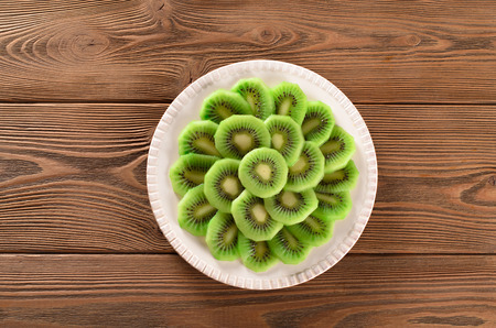 Slices of kiwi on a white plate, top viewの写真素材