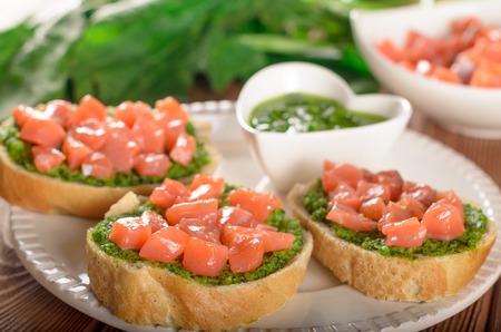 Tasty bruschetta with pieces of fresh salmon and pesto sauceの写真素材