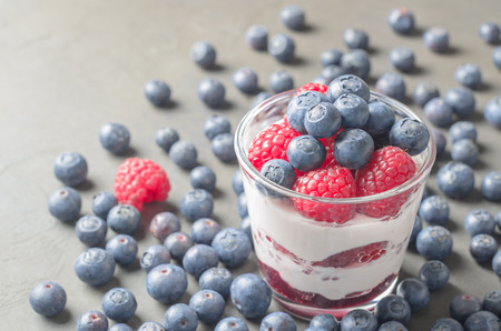 Homemade yogurt with raspberries and blueberries on a gray background. Closeup, copy spaceの写真素材