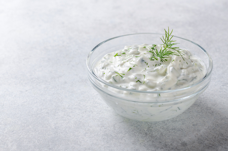 Homemade greek tzatziki sauce in a glass bowl on a light stone background. Close-up, horizontal image, copy spaceの写真素材
