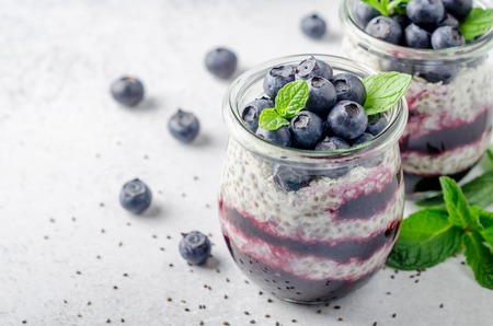 Chia pudding with blueberry and jam, two portions in glass jars on a light table. Horizontal image, copy space, high angle view, close-upの写真素材