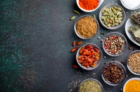 Various spices in glass bowls on a dark stone background with copy space, top view, horizontal imageの写真素材