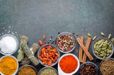 Various spices in glass bowls on a dark stone background with copy space, top view, horizontal imageの写真素材