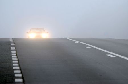 Car appearing through fog with headlights onの写真素材
