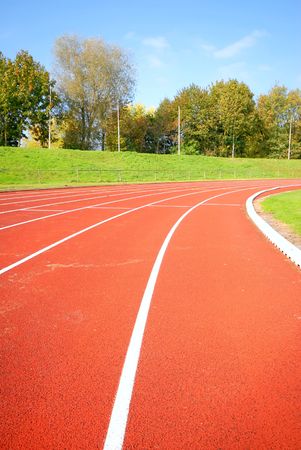 racetrack, red tarmac, for runners. trees in the background