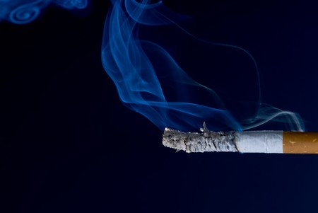 burning cigarette with smoke, isolated over blackの写真素材