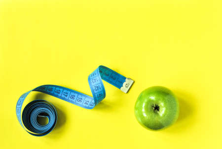A green apple and a tape on the table, diet for weight lossの写真素材