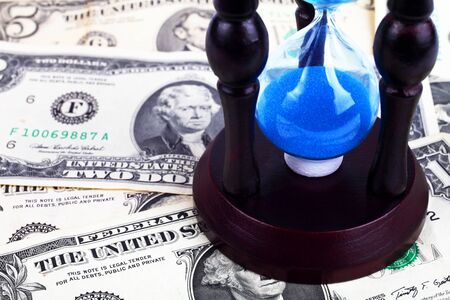 Concept, time is money. Hourglass stand on dollar bills.