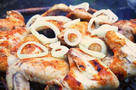 process of preparing marinated chicken wings on the grill, chopped onion rings, macroの写真素材