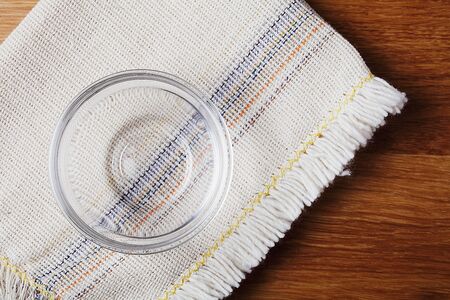 Empty glass saucepan on linen napkin, wooden tableの写真素材