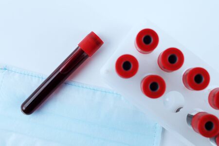 Vacuum test tubes with blood close-up on a medical mask, toned blue, soft focusの写真素材