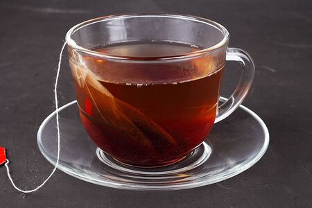 glass cup of tea with tea bag on a dark tableの写真素材