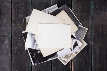 Old black and white faded photographs on a wooden background. Empty templates, mock-up.の写真素材