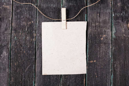Empty blank on rope with clothespin, old wooden backgroundの写真素材