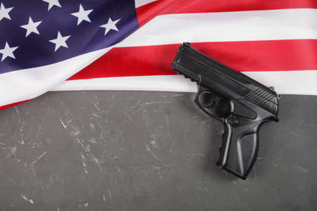 USA flag, pistol on a dark concrete background, place for your text.