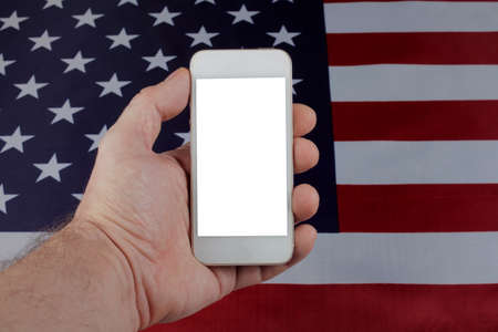 Mobile phone in a man's hand on the background of the usa flag, selective focus