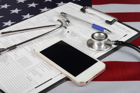 mobile phone and medical phonendoscope on american flag, close-up, selective focusの写真素材