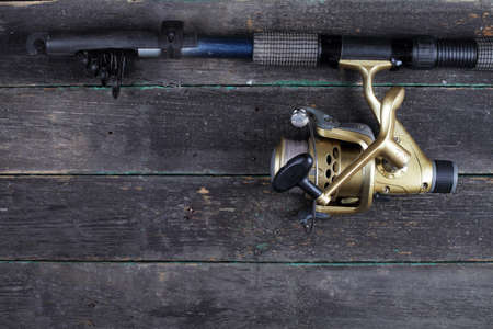 Fishing spinning with a reel of gold color on a dark background, top view, copy space.の写真素材