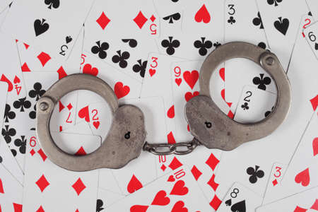 police handcuffs are on the background of game cards, top view.の写真素材