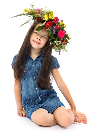 the girl of 6 years in a dark blue dress with a wreath from wild flowers on the head isolated on white の写真素材