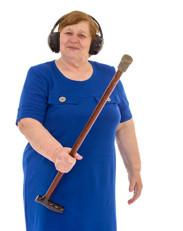 Lucky old full lady with a cane in his hand, listening to music through a large headphones, isolated on white backgroundの写真素材