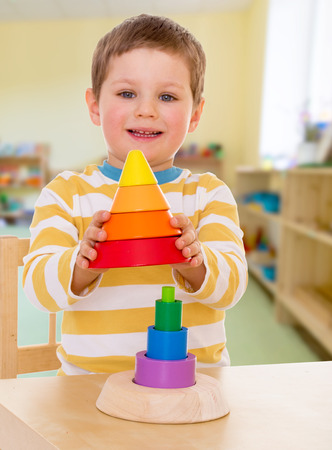little boy in kindergarten collects colorful pyramidの写真素材