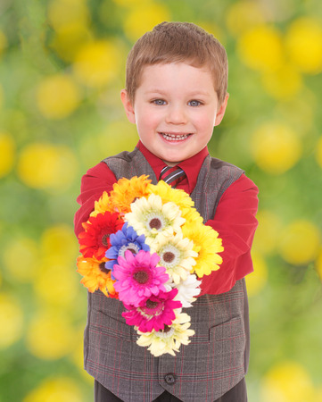 smiling little boy holding a bouquet of beautiful flowersの写真素材